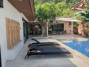 un groupe de chaises assises à côté d'une piscine dans l'établissement Villa Ravenala By S&p Villa Management, à Koh Samui 
