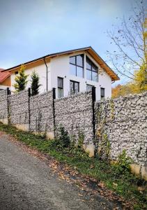 a white house behind a stone wall at Casa Runcu Dambovita in Bădeni