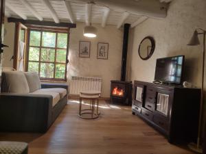 a living room with a couch and a tv and a fireplace at La Herrera ll in San Esteban de la Sierra