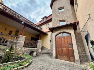a large house with a wooden door and stairs at Der OXE am Maindreieck in Niederdorla