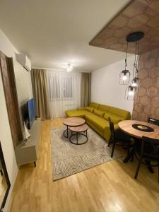 a living room with a green couch and a table at Diva apartman in Donje Mladice