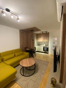 a living room with a yellow couch and a table at Diva apartman in Donje Mladice