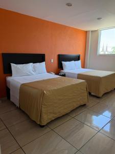 two beds in a hotel room with orange walls at ZAMORA EJECUTIVO EXPRESS in Zamora de Hidalgo