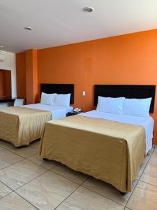 two beds in a hotel room with orange walls at ZAMORA EJECUTIVO EXPRESS in Zamora de Hidalgo