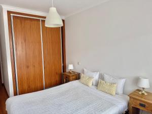 ein Schlafzimmer mit einem weißen Bett und einer Holztür in der Unterkunft Nazaré Beach Apartments in Nazaré