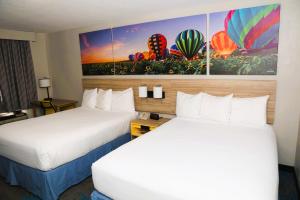 a hotel room with two beds and a painting on the wall at Days Inn by Wyndham East Albuquerque in Albuquerque +53 photos