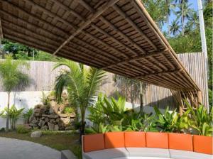 a patio with a wooden umbrella and some plants at Villa Natao by SP Villa Management in Mae Nam