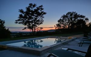 a swimming pool with a sunset in the background at Le Hameau des Lavandes in Roynac