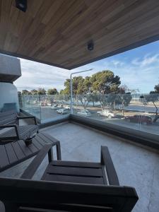einen Balkon mit Bänken und Blick auf einen Parkplatz in der Unterkunft PLAYA - Alojamiento frente al mar in Puerto Madryn + 15 Fotos
