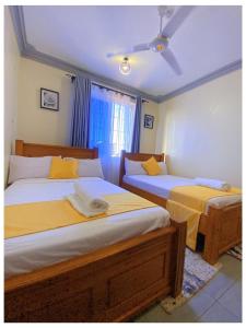 1 Schlafzimmer mit 2 Betten mit gelber Bettwäsche und einem Fenster in der Unterkunft Luxurious Pavilion Nest in Mombasa