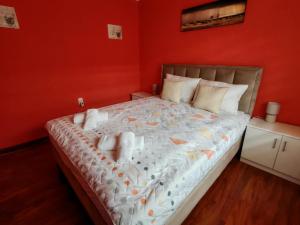 a bedroom with a large bed with orange walls at City Apartman in Subotica