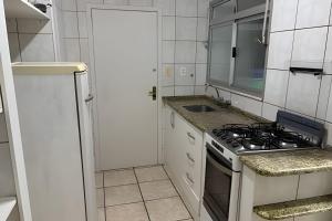 a white kitchen with a stove and a sink at Espaçoso apartamento perto Centro Sul e hospitais in Florianópolis