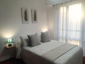 a white bedroom with a large white bed and a window at Apartamento Ziralla- con Garaje Gratis in Allariz