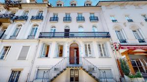 a white building with a staircase in front of it at Les Meublés d'Etigny in Luchon