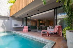 ein Haus mit einem Pool und rosa Stühlen in der Unterkunft Casa 3 Suítes Piscina e Hidro para até 9 pessoas in Tatuamunha