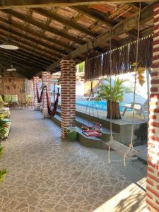 an outdoor patio with a swings and a pool at Hostel Itaparica in Itaparica Town