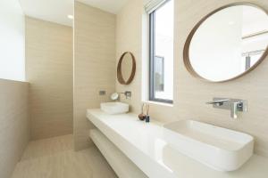 een witte badkamer met een wastafel en een spiegel bij Villa Nirvana by SP Villa Management in Koh Samui  +27 foto's