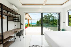 een slaapkamer met een bed en een bureau en een balkon bij Villa Nirvana by SP Villa Management in Koh Samui 