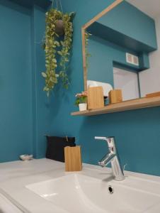 La salle de bains est pourvue d'un lavabo et d'un miroir sur un mur bleu. dans l'établissement Cote Sable Ambiance bord de mer dans le centre, à Juan-les-Pins
