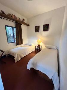 zwei Betten in einem Zimmer mit Fenster in der Unterkunft El Encino in Tepoztlán