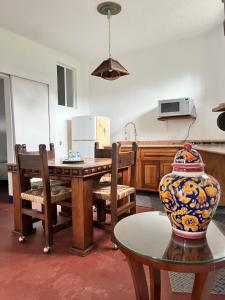 eine Küche mit einem Tisch, Stühlen und einer Vase in der Unterkunft El Encino in Tepoztlán + 9 Fotos