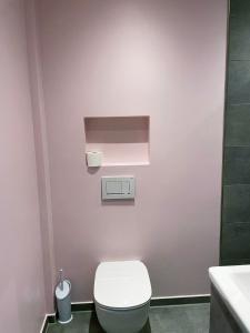 a bathroom with a toilet and a pink wall at Cozy central flat with terrace in Hinge