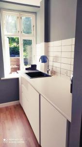 a white kitchen with a sink and a window at Cozy central flat with terrace in Hinge +5 photos
