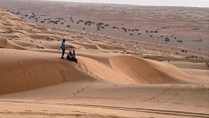 un hombre parado en una duna de arena en el desierto en Remal Chalet, en Badīyah 3 fotos más