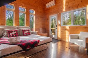 a bedroom with a bed and a couch and windows at Vacances Magiques Chalet Skadi Paix Nature in Saint-Justin