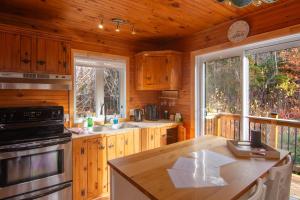 a kitchen with wooden cabinets and a stove top oven at Vacances Magiques Chalet Skadi Paix Nature in Saint-Justin