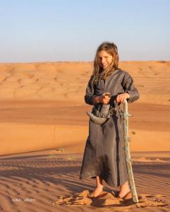 Una mujer de pie en el desierto sosteniendo un palo en Remal Chalet, en Badīyah 4 fotos más