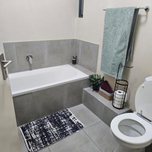 a bathroom with a bath tub and a toilet at Modern 2 bedroom at Waterfall Ridge-Midrand in Midrand
