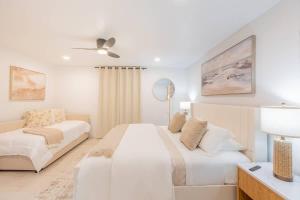 Un dormitorio blanco con dos camas y un ventilador de techo. en Ocean Pool view I Beach front I Near Flagler 2BR, en New Smyrna Beach