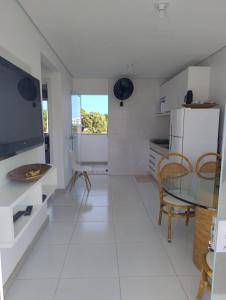 a white kitchen with a glass table and chairs at Apartamento 02 quartos - 06 pessoas in Santa Cruz Cabrália