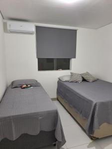 a bedroom with two beds and a flat screen tv at Apartamento 02 quartos - 06 pessoas in Santa Cruz Cabrália