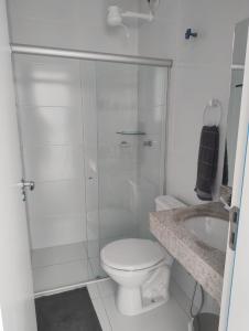 a white bathroom with a toilet and a shower at Apartamento 02 quartos - 06 pessoas in Santa Cruz Cabrália +15 photos