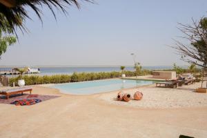 una piscina junto a la playa con dos bancos en Ecolodge Pout Pout, en Fatick