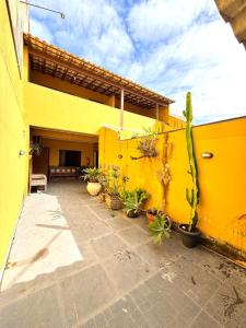 a yellow building with a bunch of potted plants at Pousada Recanto de Figueira in Arraial do Cabo