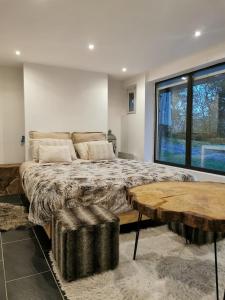 a bedroom with a large bed and a large window at The Forest Chalet - Private forest and absolute calm in Plainfaing