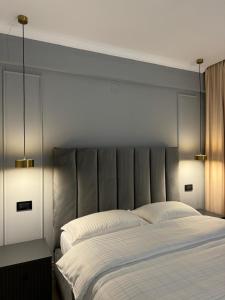 a bedroom with a large bed with two lights on it at Cuza Residence in Craiova