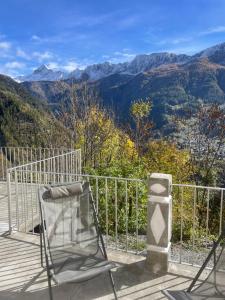 a chair on a deck with a view of mountains at La Primula Panoramic View - Valmalenco in Chiesa in Valmalenco