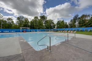 a large swimming pool with chairs and a blue wall at Cassopolis Cabin with On-Site Fishing Pier! in Cassopolis