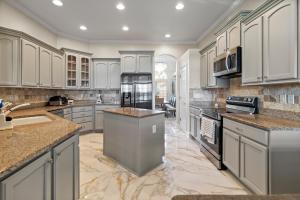 a large kitchen with white cabinets and granite counter tops at Riverfront Escape! Private Pier, 4 BR Home and Room to Entertain in Jacksonville