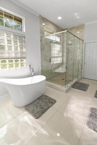 a bathroom with a tub and a glass shower at Riverfront Escape! Private Pier, 4 BR Home and Room to Entertain in Jacksonville +28 photos