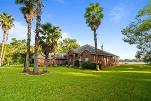 a house with palm trees in front of it at Riverfront Escape! Private Pier, 4 BR Home and Room to Entertain in Jacksonville