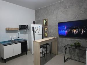a kitchen with a refrigerator and a table and a tv at Jardim Primavera in Palmas