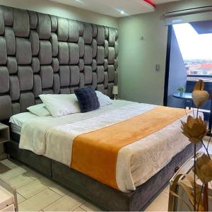 a bedroom with a large bed with a large padded headboard at Hotel Funza Real in Funza