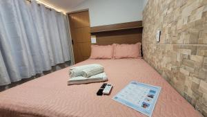 a bed with a remote control on top of it at Pousada Sol e Descanso by Easy Hotéis in Arraial do Cabo