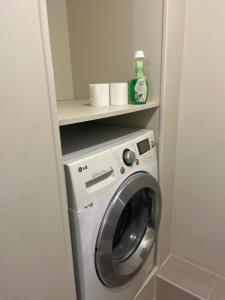 a washing machine in a bathroom with a shelf at cosy studio dans une maison d'hôte in Bourg-en-Bresse