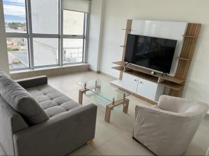 a living room with a couch and a flat screen tv at Ecos del Mar in Comodoro Rivadavia